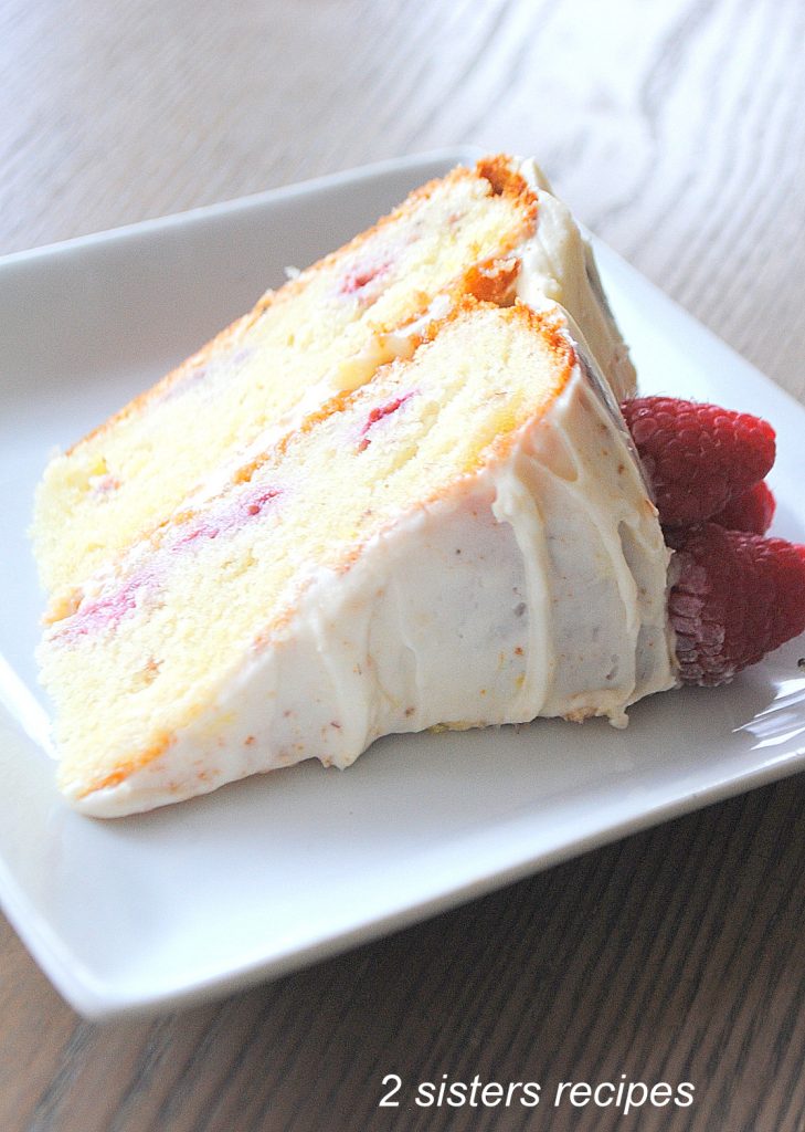 A slice of white cake with icing on a white plate.