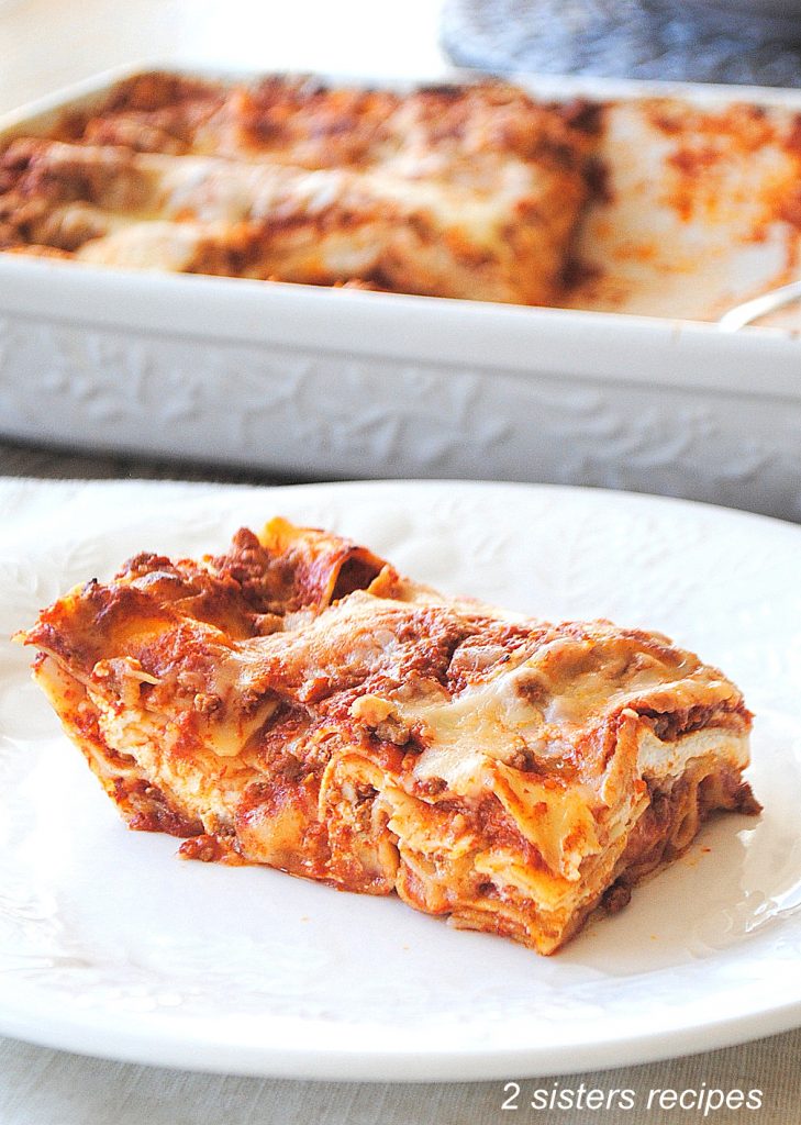 A slice of lasagna on a white dinner plate.