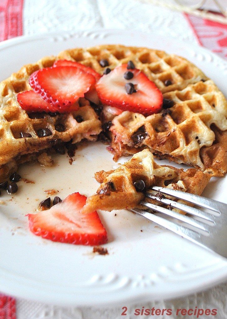 A forkful of waffle with strawberries and mini chocolate chips on top. 