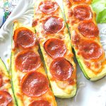 There are 4 Zucchini Pepperoni Pizza Boats served on a white platter.