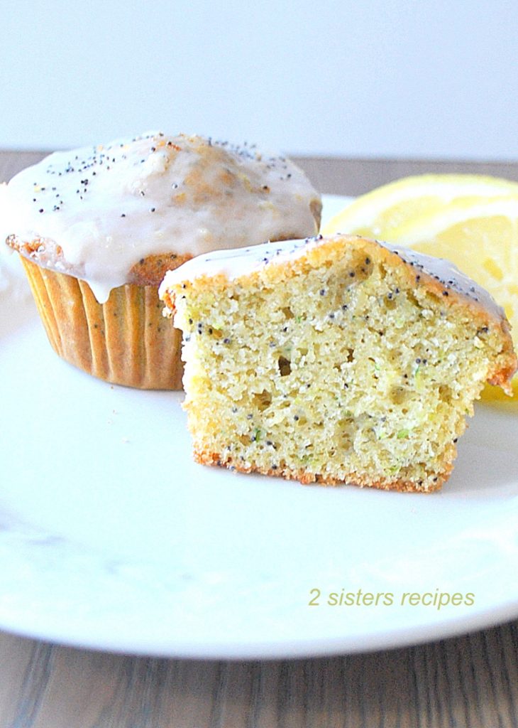 A lemon muffin sliced in half and served on a white plate.