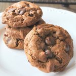 3 chocolate chip cookies piled on a white plate.