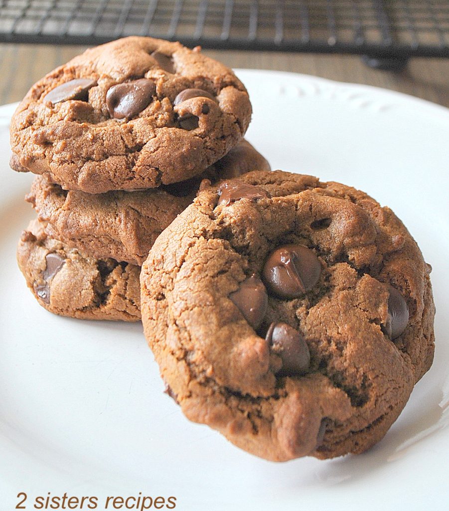 3 chocolate chip cookies piled on a white plate.