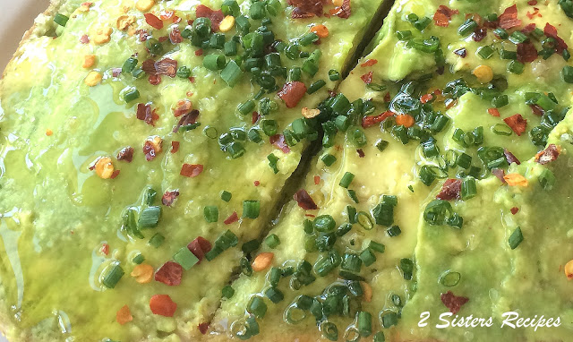 An avocado toast with mashed avocado, red pepper flakes and fresh chives on top.