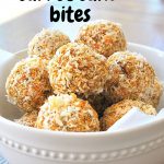 A white bowl filled with orange colored balls coated with shredded coconut.