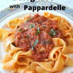 A white and blue dinner plate filled with pappardelle noodles with a thick, chunky vegetable tomato sauce on top.
