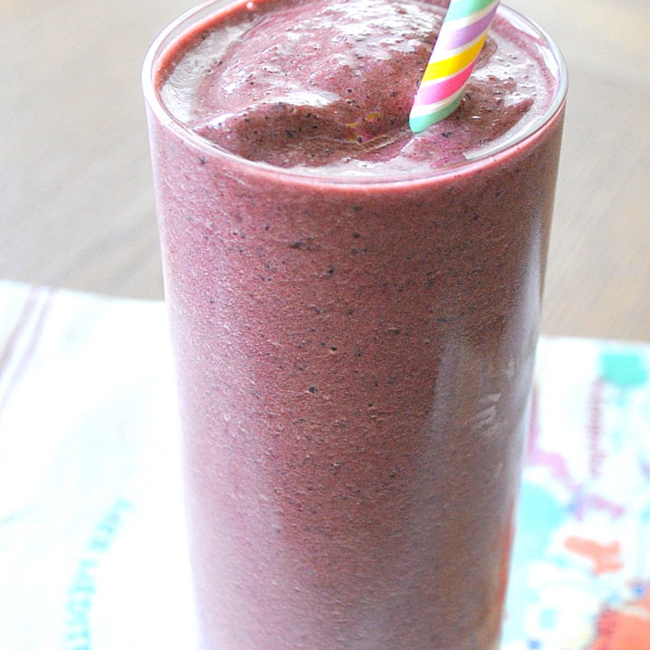Beet Spinach Protein Smoothie is served in a tall glass with a colored stripe straw.
