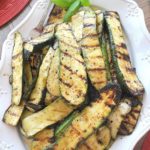 A white platter filled with grilled sliced zucchini.