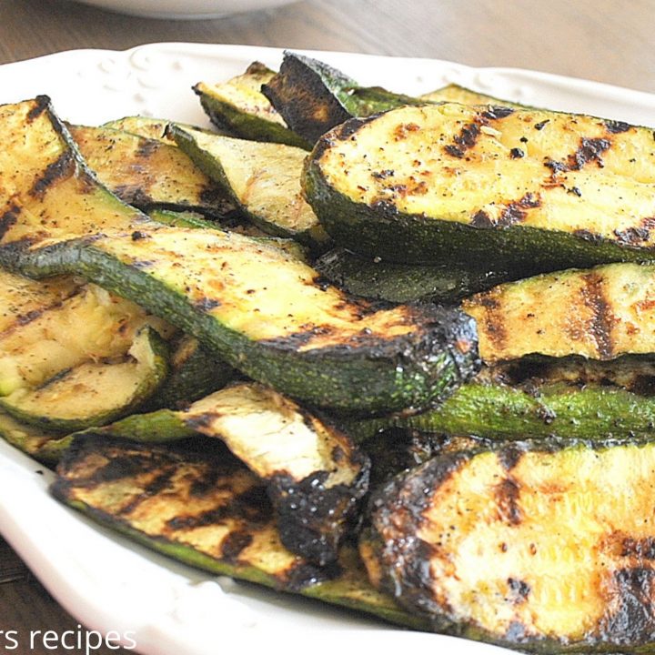 A serving of grilled zucchini on a white platter.