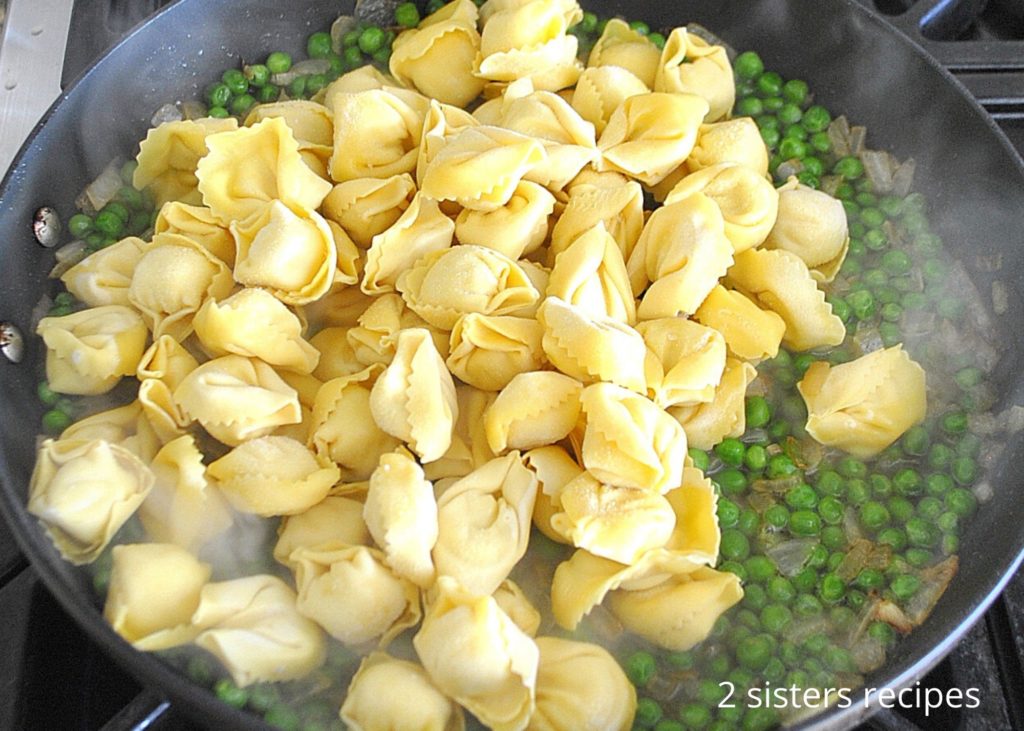 frozen tortellini in a skillet with peas and onions. by 2sistersrecipes.com 