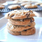 A pile of baked chocolate chip cookies set on a white plate.