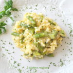 A white plate with a serving of creamy Asparagus Risotto with fresh parsley scattered over it.