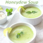 Two small white ramekins filled with a light green color soup, Topped with some mint.