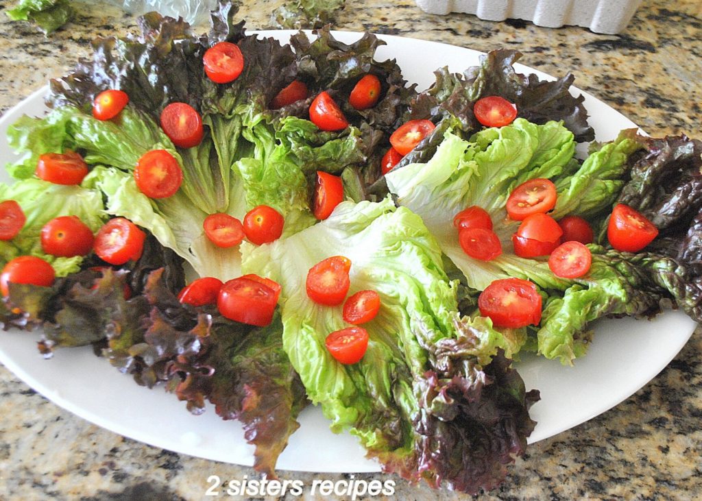 Red leafy salad with cherry tomatoes on platter. by 2sistersrecipes.com 
