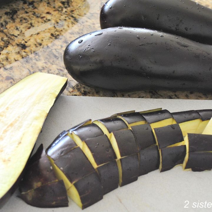 An eggplant cut into cubes on a cutting board. by 2sistersrecipes.com