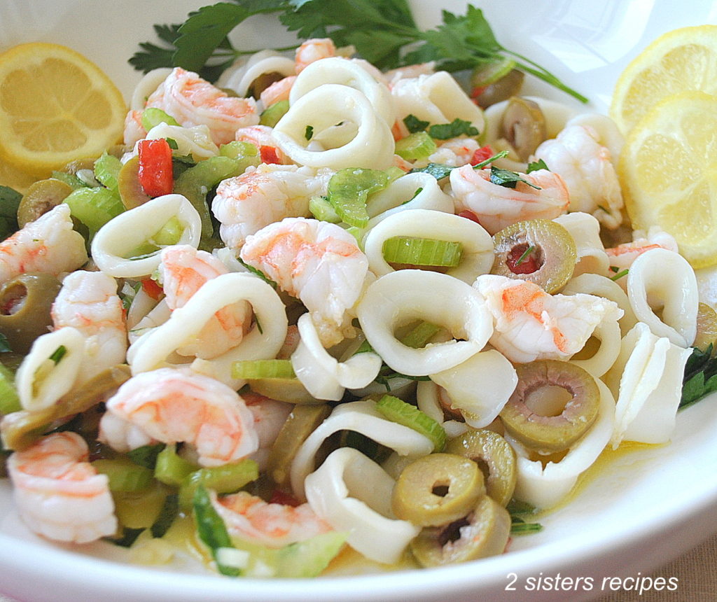 Shrimp and Calamari Salad are served in a white salad bowl with lemon wedges.