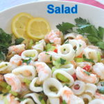Shrimp and Calamari Salad served in a white bowl with lemon slices and parsley leaves.