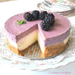 A double layer cheesecake with crust and a layer of blackberry flavor on top.