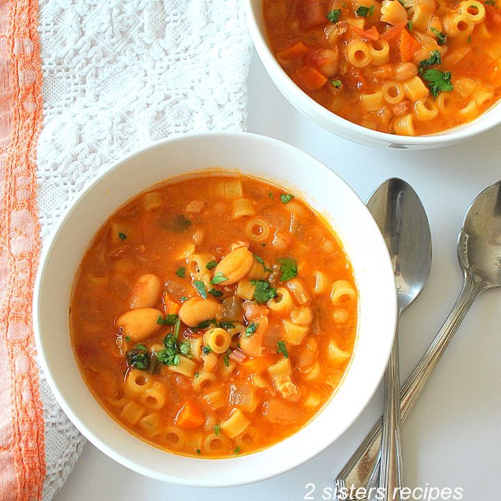 A white bowl of pasta fagioli soup. by 2sistersrecipes.com