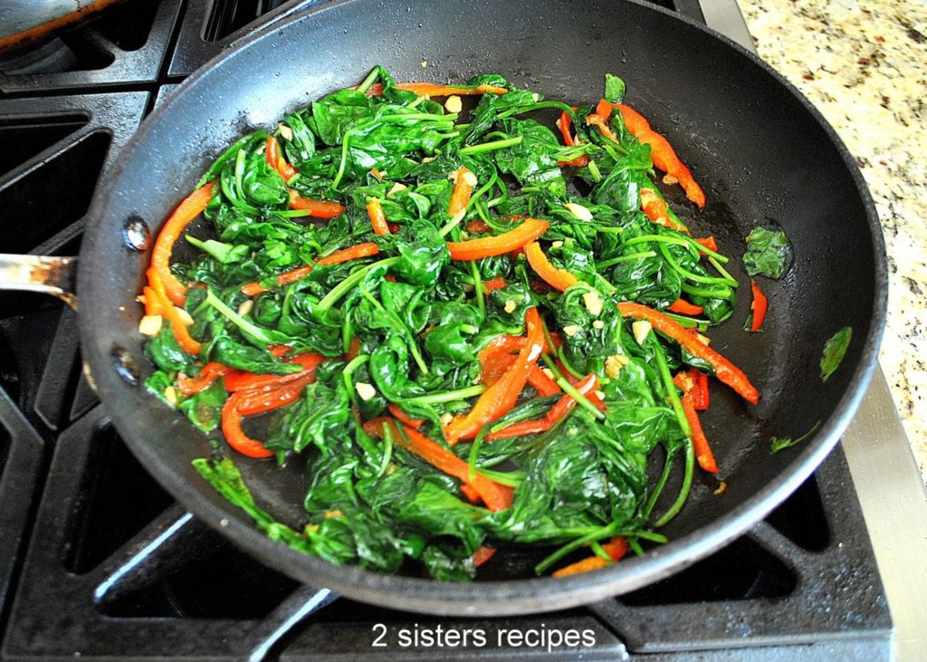 Cooking spinach with red bell peppers in a skillet. by 2sistersrecipes.com 