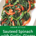 A white rectangular serving platter filled with cooked spinach and red peppers.