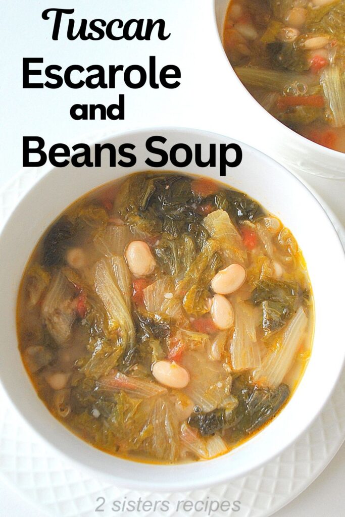 A white soup bowl filled with white beans, escarole and tomatoes in a broth.