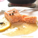 A piece of salmon with capers, and lemon sauce.