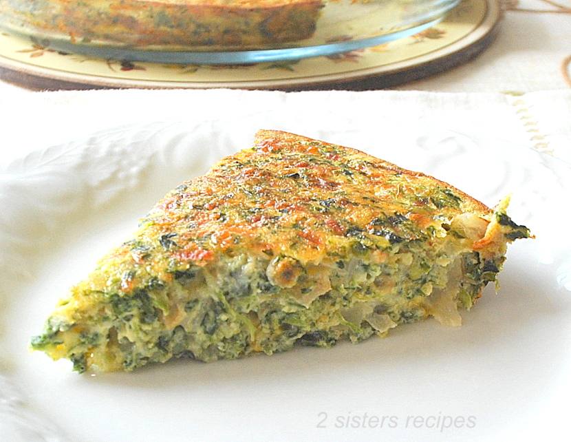 A serving portion of a spinach and cheese quiche served on a white plate.