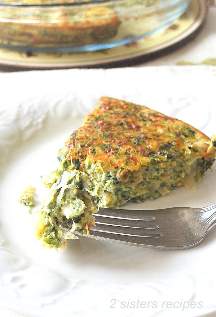 A forkful of spinach and cheese filled quiche on a white plate.