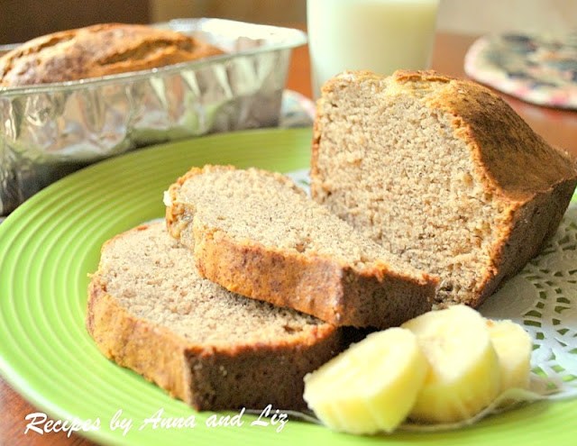 A sliced banana bread with sliced bananas on a green plate.