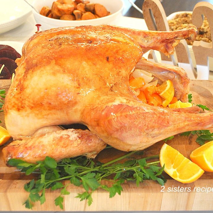 A fully roasted turkey resting on a wood carving board.