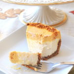 A forkful of pumpkin cheesecake served on a white square plate.