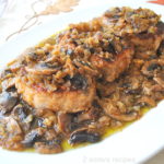 On a white platter, three pork chops served with a mushroom sauce on top.
