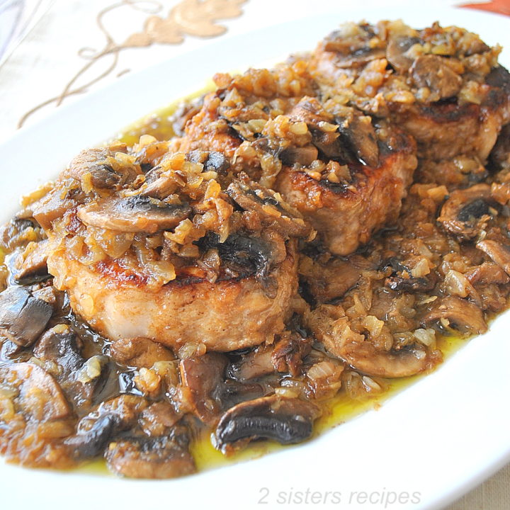 On a white platter, three pork chops served with a mushroom sauce on top.