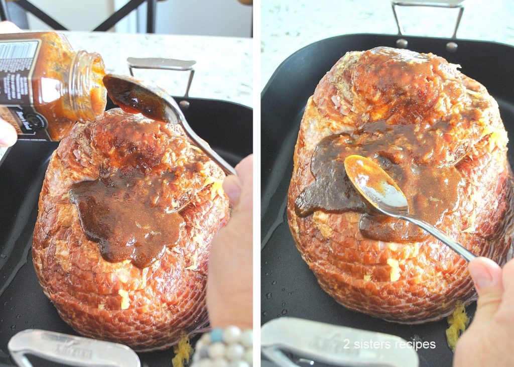 Glazing the spiral ham with a jar of glaze and a spoon.