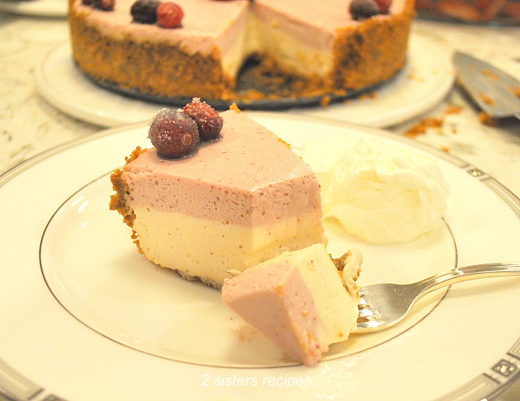 A slice of holiday cranberry cheesecake on a white plate. by 2sistersrecipes.com 