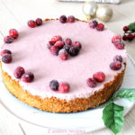 A cheesecake with a layer of cranberry flavor on top and sugar cranberries as garnish.