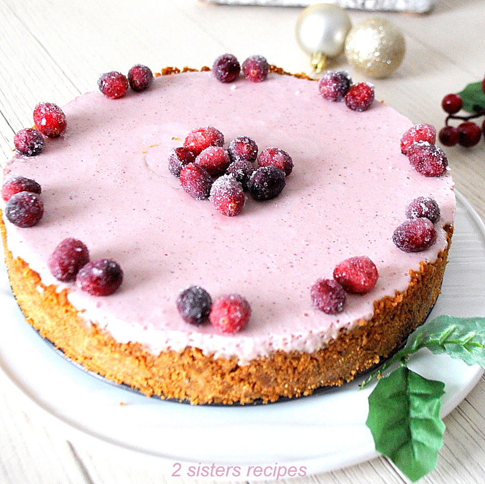 A cheesecake with a layer of cranberry flavor on top and sugar cranberries as garnish.