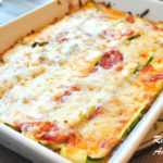 A white baking dish with a zucchini lasagna covered with melted cheese.