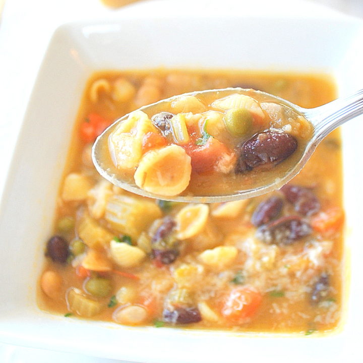 A spoonful of soup with mini pasta shells with beans and vegetables.