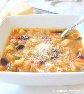 A bowl of minestrone soup with a spoonful in the bowl.
