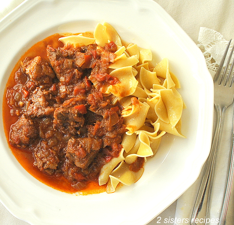 A plate filled with noodles and beef stew.