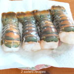 Four raw lobster tails sitting on a paper towel, draining.