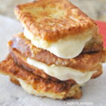 Three small crispy sandwiches with melted mozzarella in between piled on top of one another