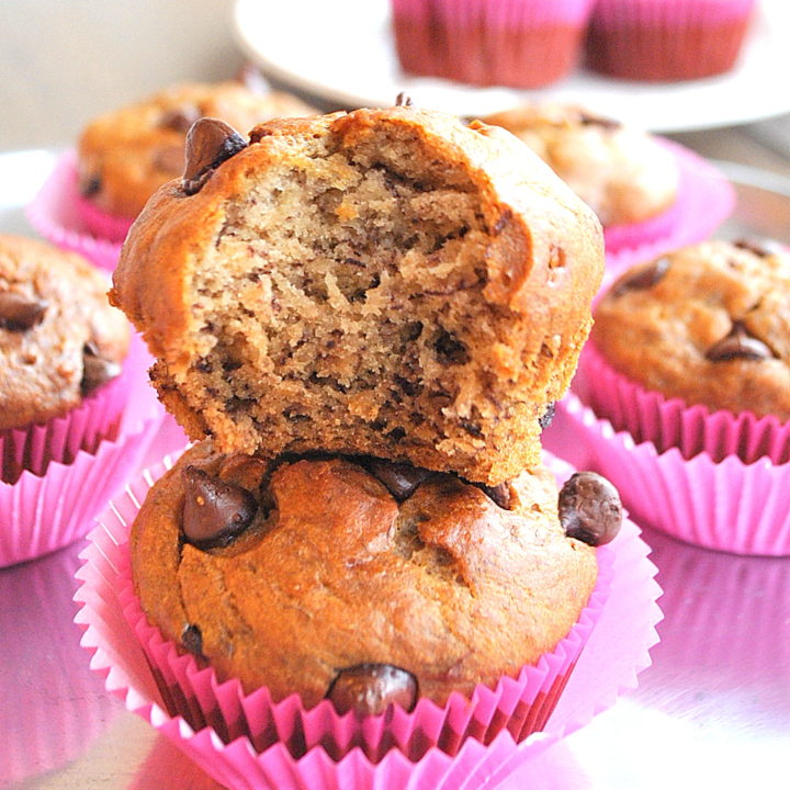 2 Paleo Banana Chocolate Chip Muffins on top of each other with a bite in one by 2sistersrecipes.com
