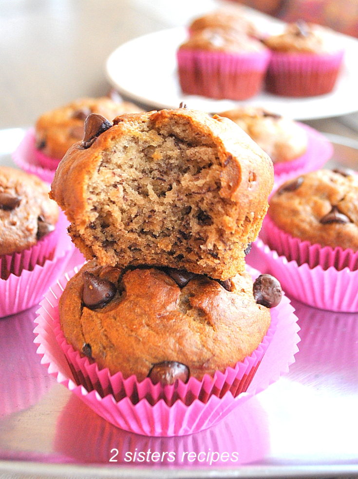 2 Paleo Banana Chocolate Chip Muffins on top of each other with a bite in one by 2sistersrecipes.com