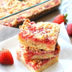 Strawberry Crumble Bars are piled on top of one another, served on a small plate.
