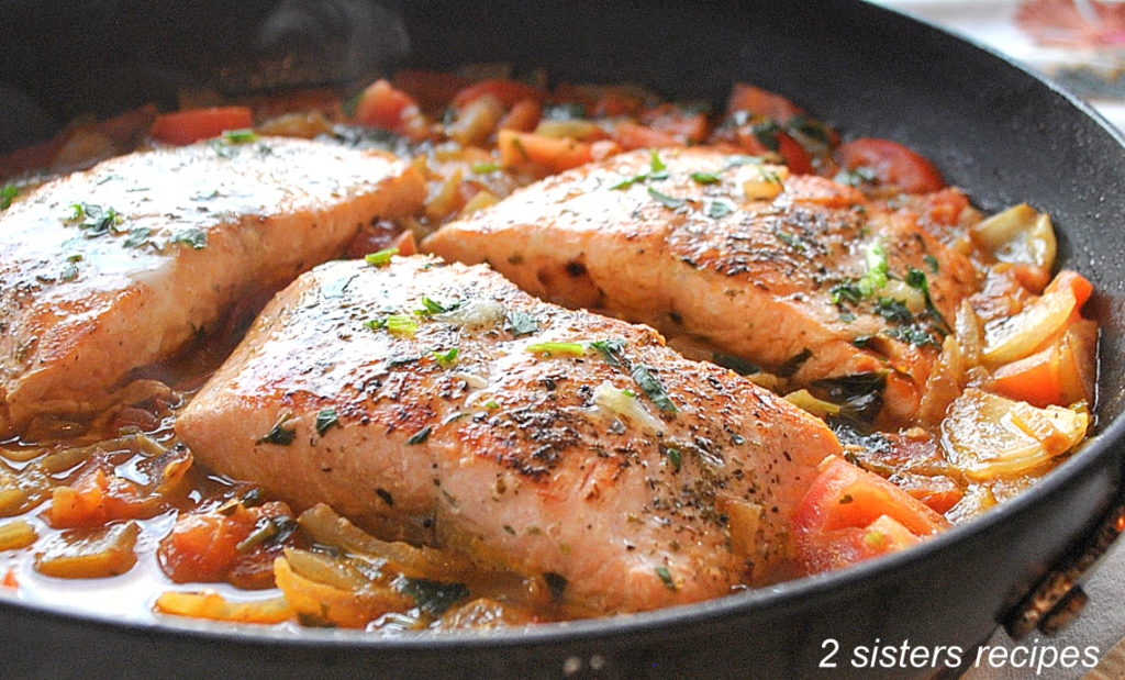 Pan seared salmon cooked in skillet with the tomato sauce. by 2sistersrecipes.com