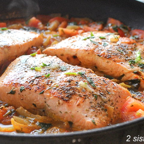 Pan seared salmon cooked in skillet with the tomato sauce.