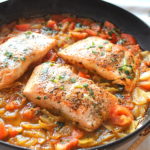Pan-Seared Salmon with Tomato-Onion served in a black skillet.